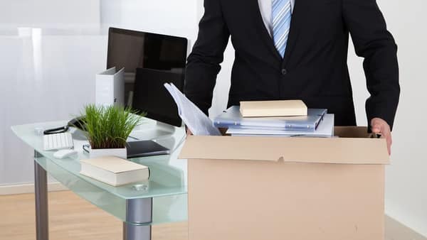 Person packing office items into a carton at a desk