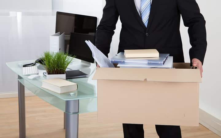 Office files and supplies being packed into a carton at a desk